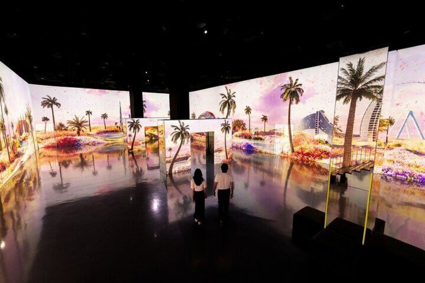 Una gran instalación artística en interiores con suelos reflectantes y paneles coloridos que muestran paisajes tropicales con palmeras y flores. 5