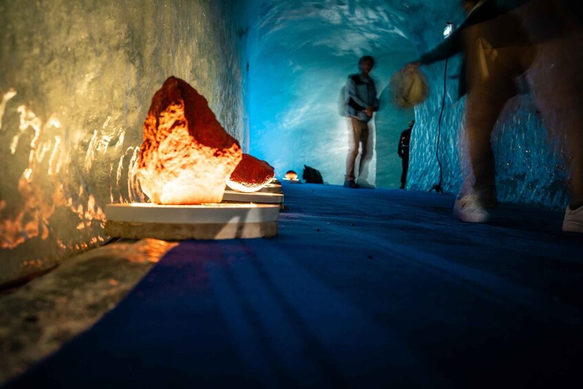 A cave with a glowing rock and a person carrying a bag. 3