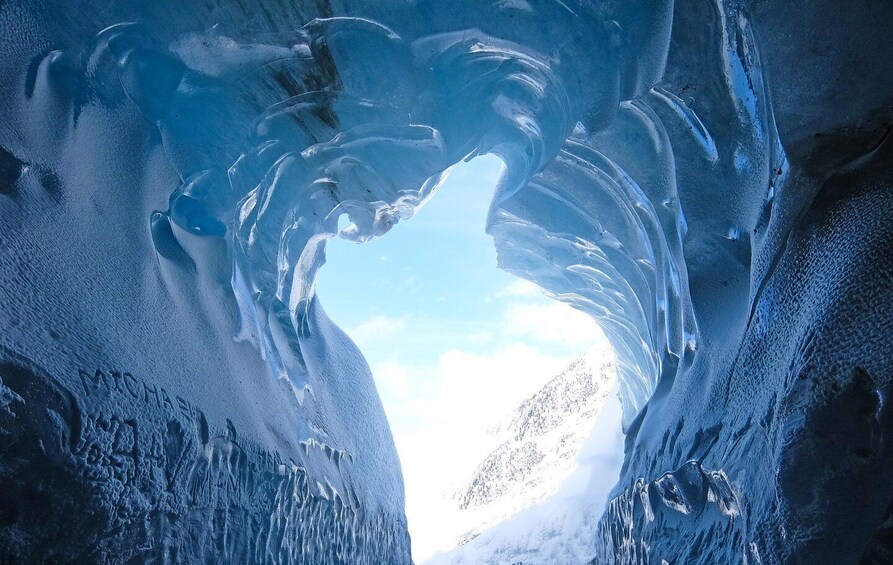 An ice cave with a clear sky visible through the opening. 2