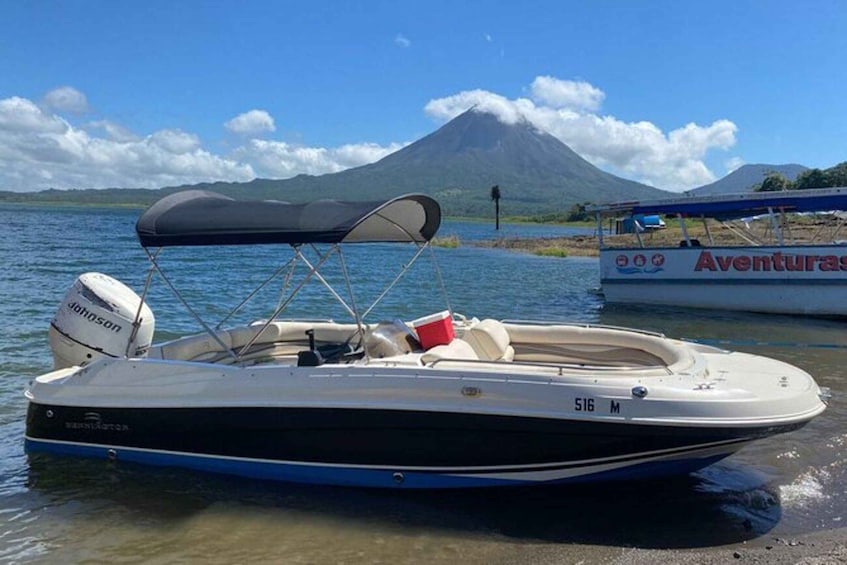 A boat named '516 M' with a black and white color scheme, docked near a beach with a mountain in the background. 5