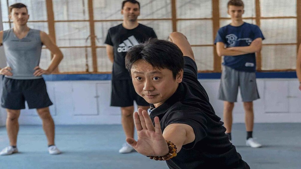 A martial arts class with four participants in a gym. 1
