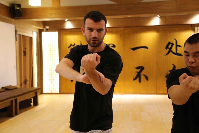 Two people practicing martial arts in a room with wooden walls and tatami flooring. 3
