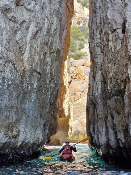 A kayaker navigating through a narrow canyon with towering rock walls. 5