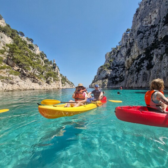 People kayaking on a clear turquoise sea with rocky cliffs. 5