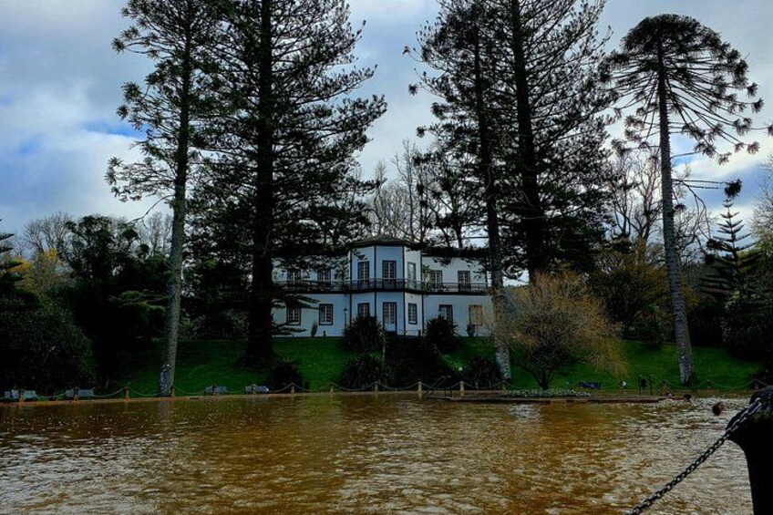 A house surrounded by tall trees and a body of water. 2
