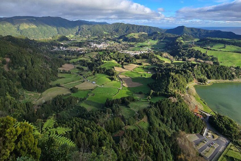 A mountainous landscape with a town, green fields, and a lake. 3