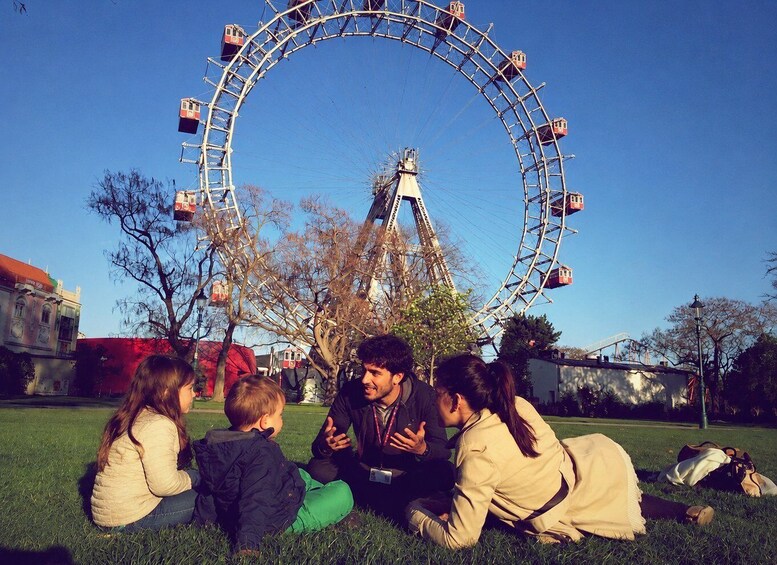 A family sitting on grass with a Ferris wheel in the background. 3