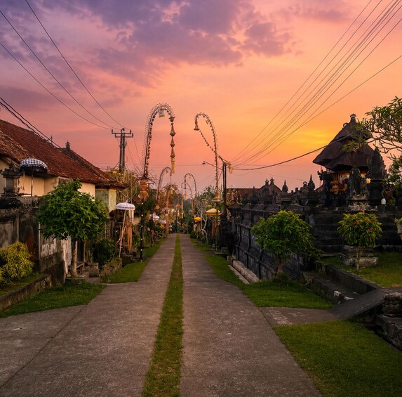 A sunset over a village street lined with traditional houses and temples. 4