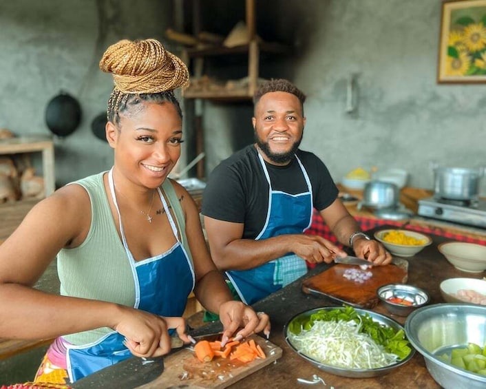 Two people preparing food, with vegetables and kitchen utensils on the table. 5