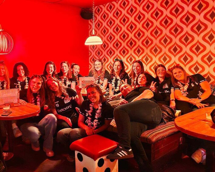 A group of people sitting around tables in a room with red and patterned wallpaper. 4