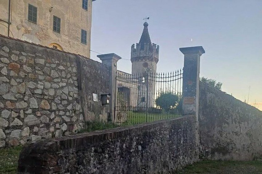 A stone wall, a metal gate, and a tower with a spire. 3