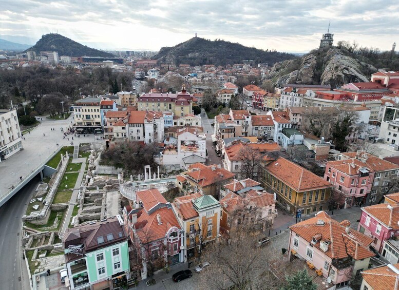 A cityscape with historic buildings, a prominent hill with a tower, and a modern bridge. 5