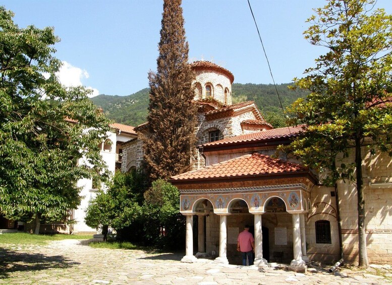A historic building with a red-tiled roof, surrounded by trees and a cobblestone path. 2