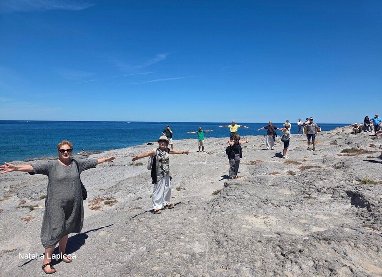 A group of people performing a yoga pose on a rocky beach with the ocean in the background. 2