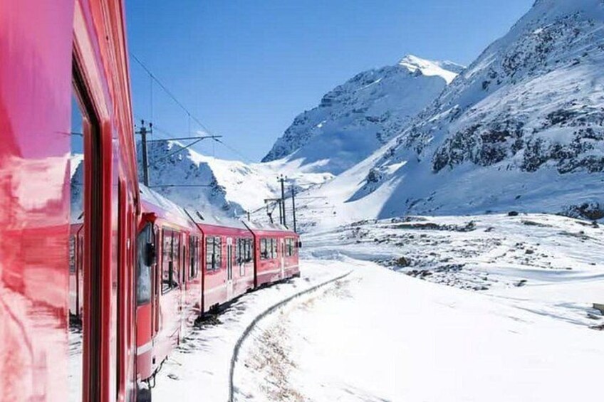Un tren rojo sobre rieles que atraviesa un paisaje montañoso nevado. 2