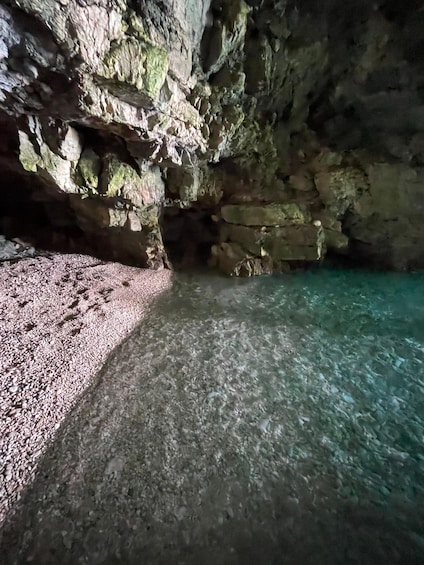 A cave with rocky walls and a pebble beach. 2