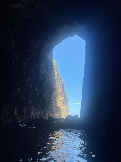A cave entrance with a clear view of the sky and water below. 3