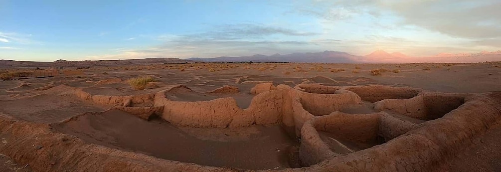 A dry, expansive landscape with terraced formations and distant mountains under a clear sky. 3