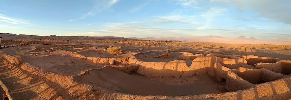 A desert landscape with terraced formations and a distant mountain range. 2