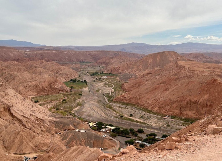 A rugged canyon landscape with a winding river, sparse vegetation, and scattered buildings. 1