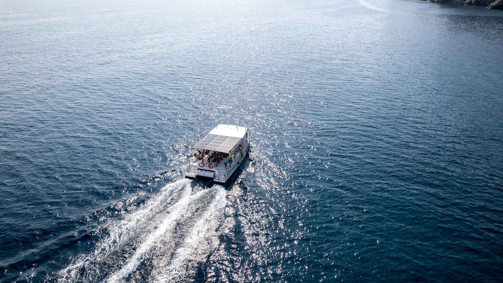 A boat with a covered deck sailing on a calm body of water. 3