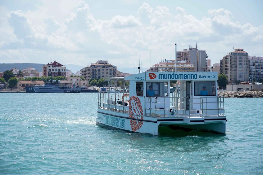 A boat named 'mundomarin' with a helipad and a logo on its side, floating on water with a cityscape in the background. 5