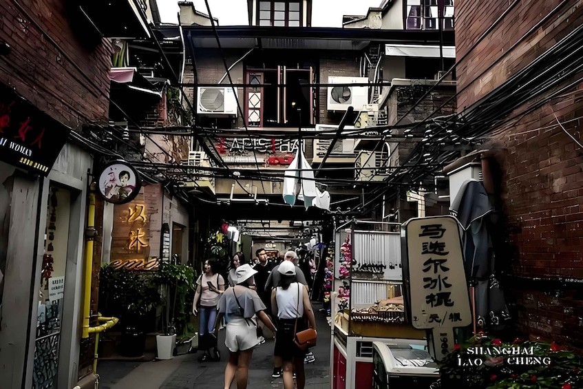 A narrow alley with shops and hanging signs, crowded with pedestrians. 5