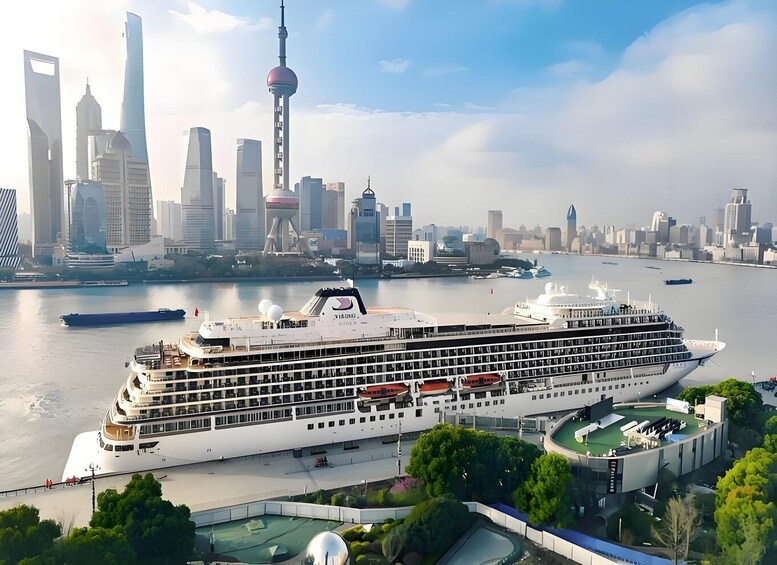 A large cruise ship docked near a city skyline with modern skyscrapers and a prominent tower. 3