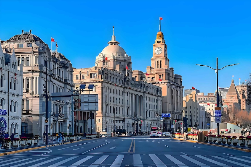 A wide street with a prominent building featuring a dome and a clock tower. 2