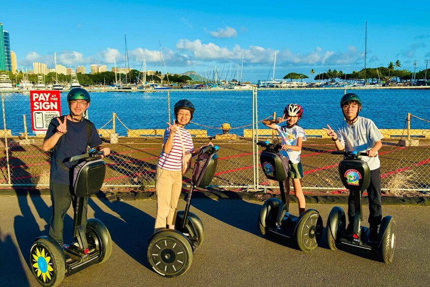 Four people on segways near a waterfront with a sign that says 'PAY AT THIS SIGN'. 3