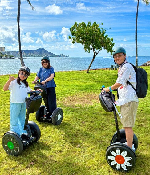 Three people on segways by a waterfront with a mountain in the background. 2