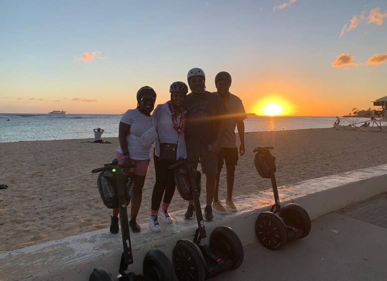 A sunset at the beach with four people and two Segways. 1