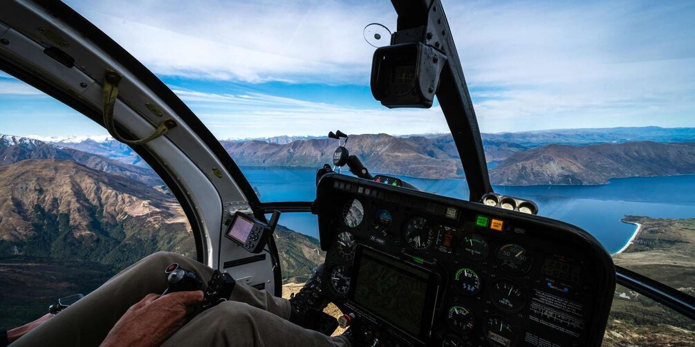 A helicopter cockpit with a mountainous landscape and a lake in the background. 3