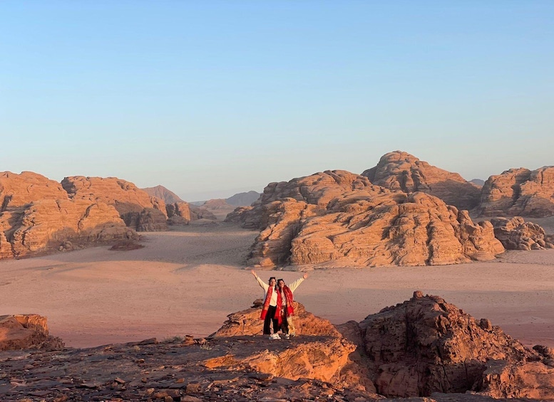 A person standing on a rocky outcrop with a desert landscape in the background. 1