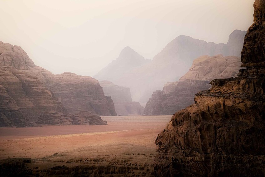 A desert canyon with layered rock formations and a riverbed. 1
