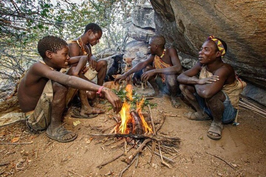 Four people sitting around a campfire in a natural setting. 5