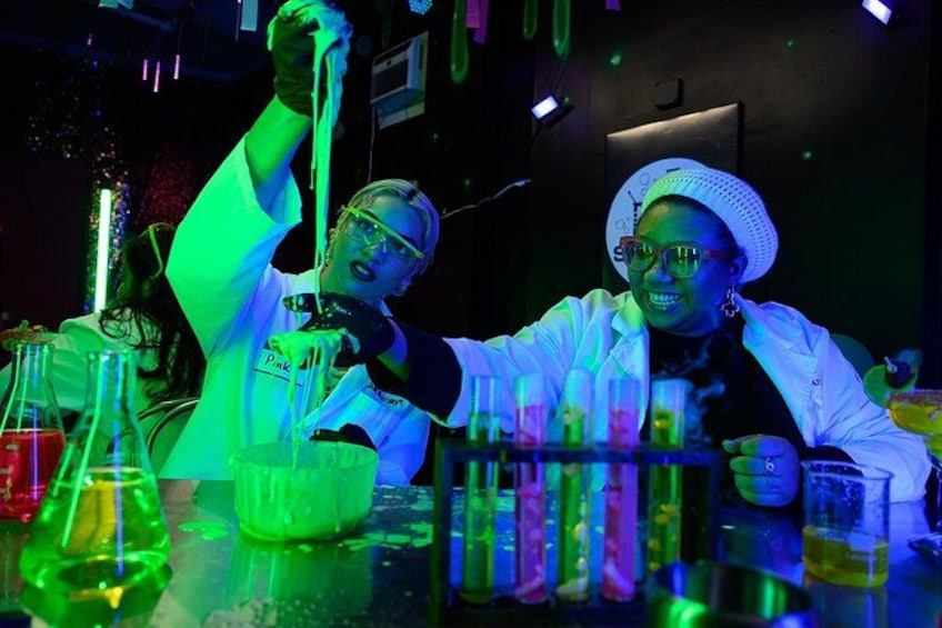 Two people in lab coats conducting an experiment with colorful liquids in test tubes. 4