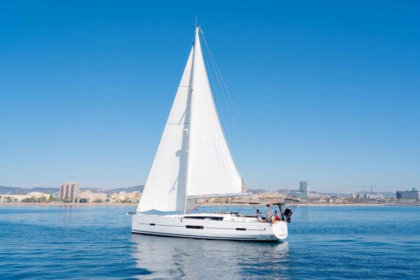 A white sailboat on calm waters with a city skyline in the background. 2