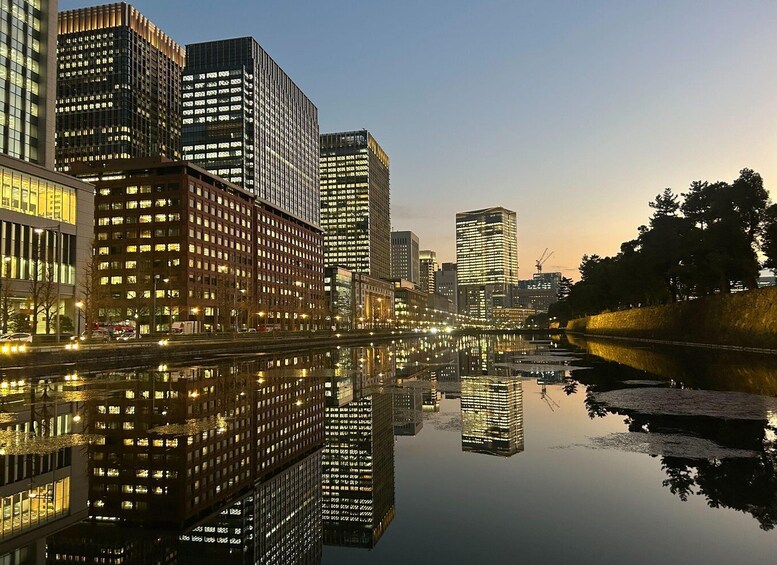 A cityscape with high-rise buildings reflecting on a calm body of water during twilight. 4