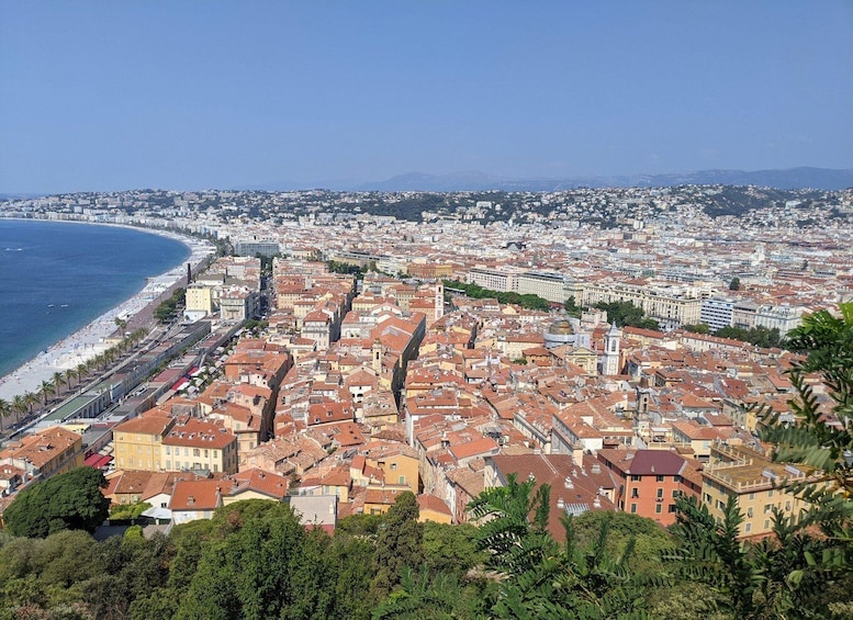 A coastal cityscape with a dense urban area, a beach, and a clear blue sky. 1