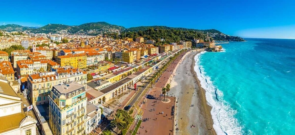 A coastal cityscape with a beach, buildings, and a clear blue sea. 2