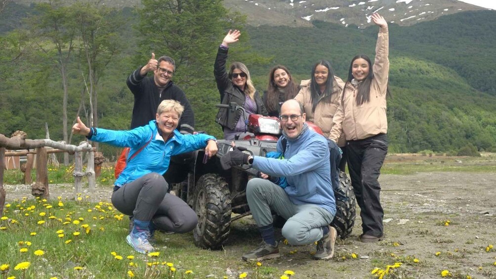 A group of people posing with a quad bike in a mountainous area with dandelions on the ground. 4