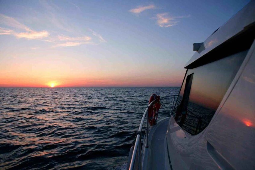 A boat at sunset with the sun near the horizon over the ocean. 2