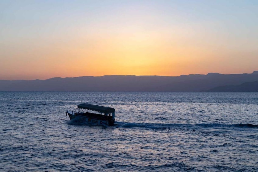 A boat moving across a body of water during sunset. 5
