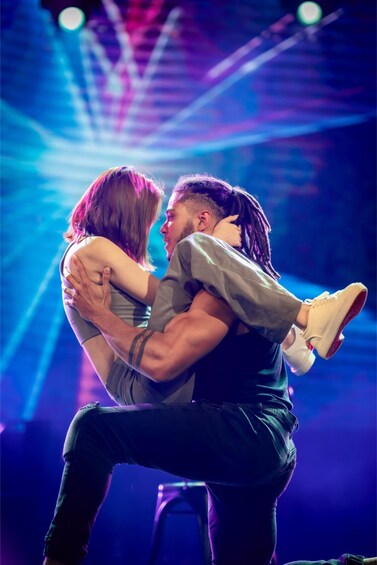 Two people embracing on a stage with stage lights in the background. 2