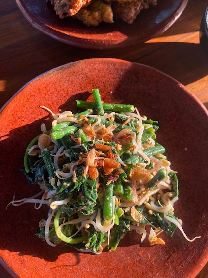 A plate of green vegetables with noodles and fried onions. 5
