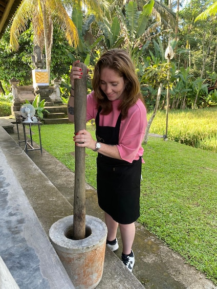A person using a traditional mortar and pestle outdoors. 3