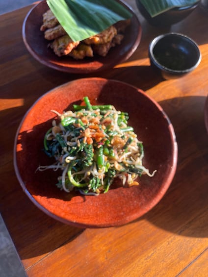 A bowl of stir-fried vegetables with peanuts and bean sprouts on a red plate. 4