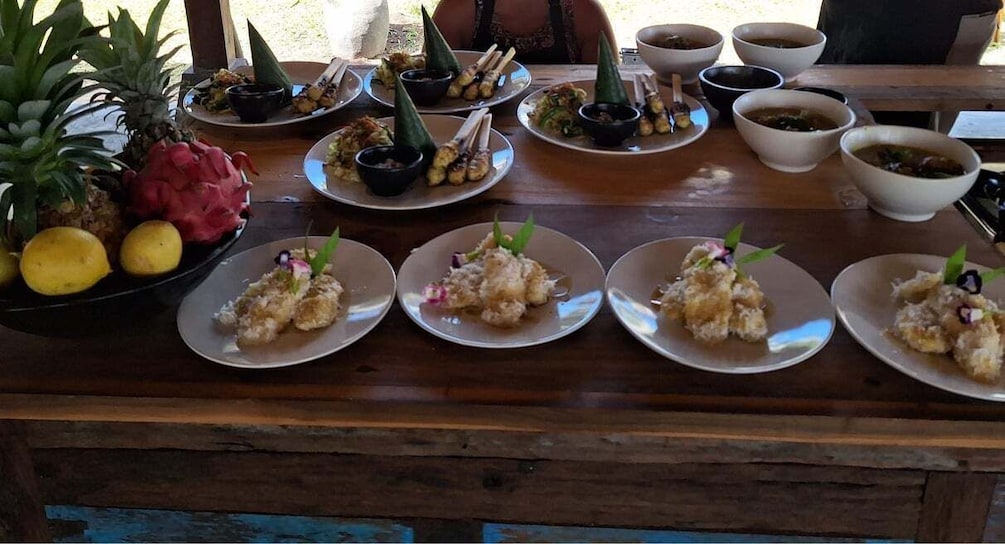 A wooden table with plates of food, including conical food items and a pineapple. 1