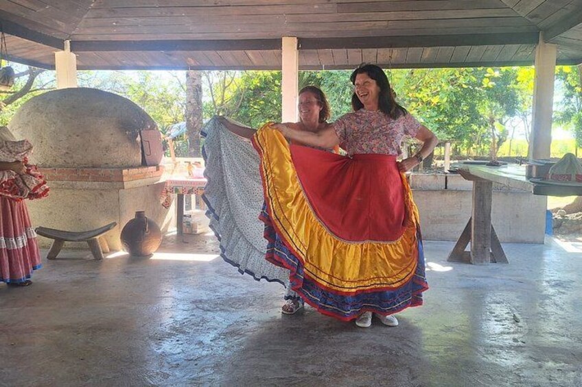 Two people in traditional attire, a stone oven, and a covered outdoor area. 2
